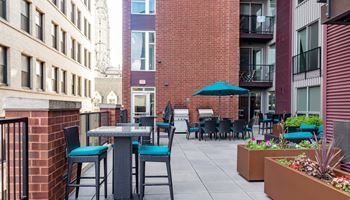an outdoor patio with tables and chairs at the bradley braddock road station apartments